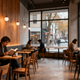 Commercial lighting design tips in a cozy cafe setting with customers reading and enjoying coffee.